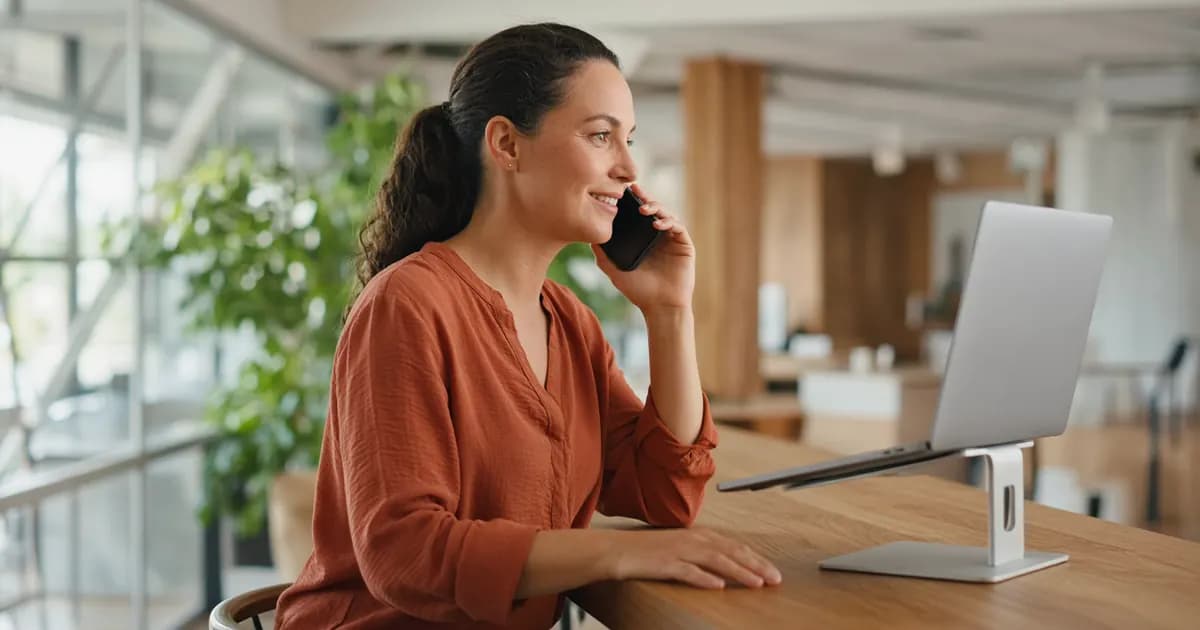 Property manager smiling while looking at her laptop screen and taking a friendly phone call about a non-urgent request