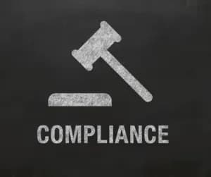 A chalk drawing of a gavel on a blackboard above the word compliance